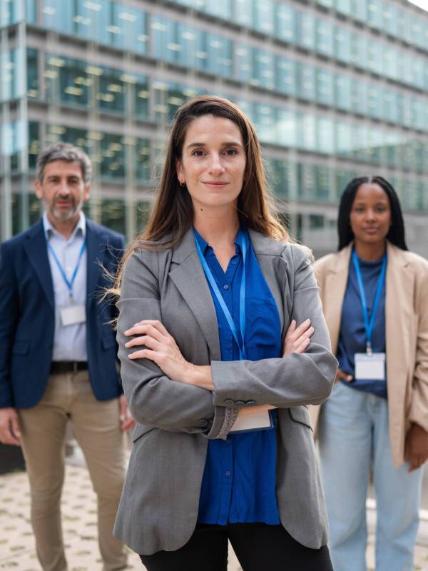 Diverse business team of professionals standing confidently in front of a modern office building